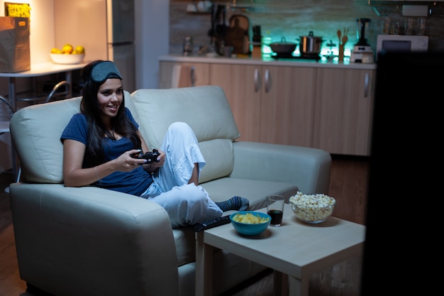 Bezpłatne zdjęcie zdeterminowana kobieta grająca w gry wideo w salonie w nocy