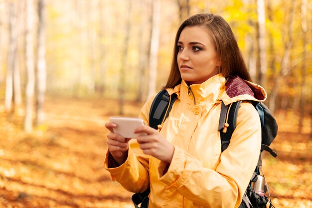 Zdezorientowany młody turysta z inteligentny telefon w lesie