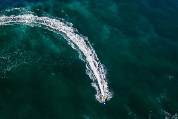 Zdjęcia lotnicze osoby na nartach wodnych w jasnozielonej wodzie morskiej