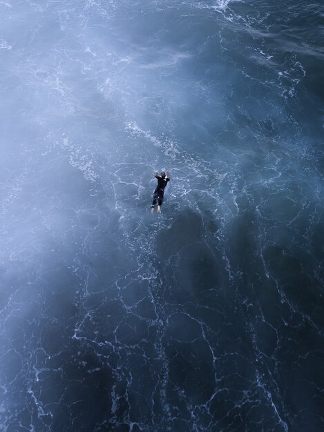 Zdjęcia lotnicze z pięknym krajobrazem i osobą pływającą w morzu w słońcu