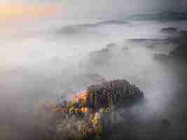 Bezpłatne zdjęcie zdjęcia lotnicze zalesionej góry otoczonej mgłą, tła wielkiego fora lub bloga