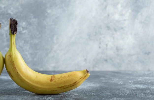 Zdjęcie dojrzałego żółtego banana na szarym tle.