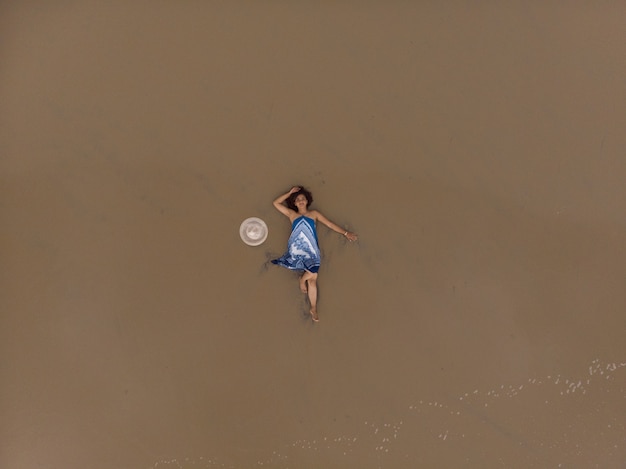 Zdjęcie lotnicze azjatyckiej kobiety leżącej na piaszczystej plaży
