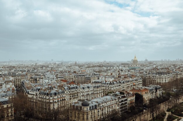 Zdjęcie lotnicze Paryża pokrytego zielenią i budynkami pod zachmurzonym niebem we Francji