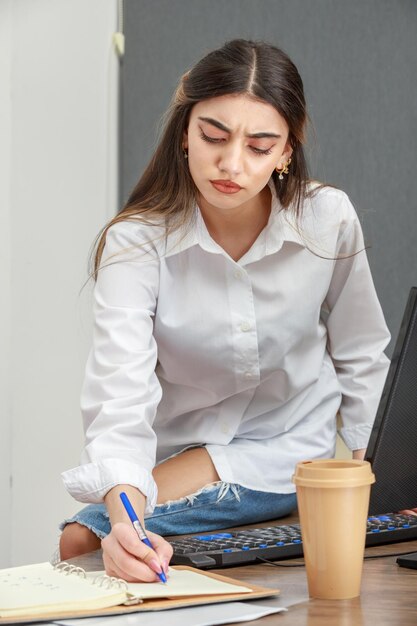 Zdjęcie młodej bizneswoman robiącej notatki w biurze Zdjęcie wysokiej jakości