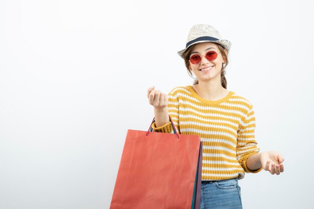 Zdjęcie młodej kobiety brunetka w okularach przeciwsłonecznych, trzymając torby na zakupy. Zdjęcie wysokiej jakości