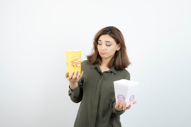Zdjęcie młodej kobiety w stroju casual, trzymając popcorn. Zdjęcie wysokiej jakości