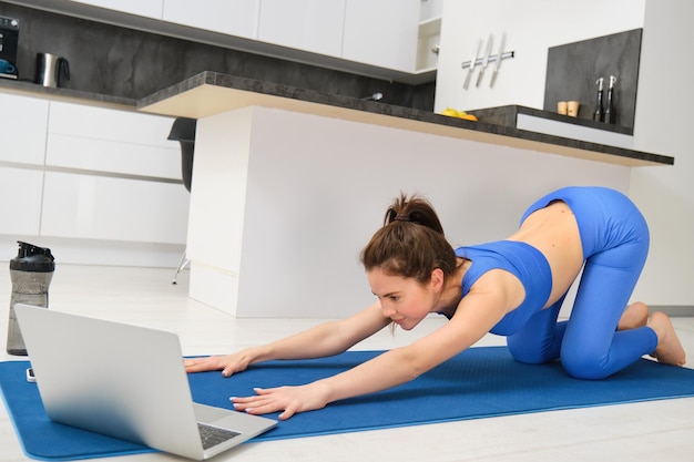 Zdjęcie Młodej Sportowca Fitness Dziewczyna Oglądając Online Yoga Tutorial Na Laptopie I ćwiczenia