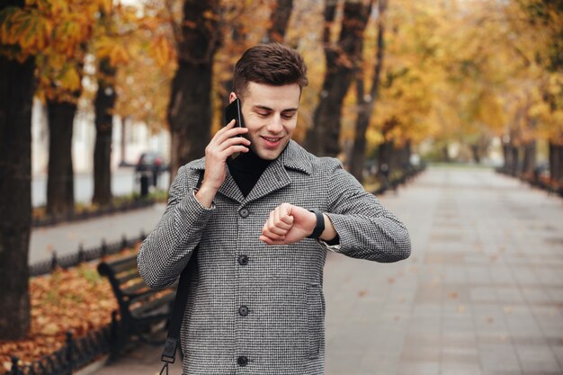 Zdjęcie pomyślnego biznesmena mówiący na telefonie komórkowym, podczas gdy iść na spotkanie w czasie