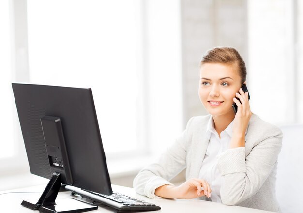 Zdjęcie uśmiechniętej bizneswoman ze smartfonem w biurze
