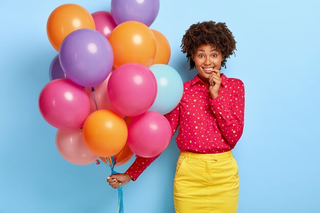 Zdjęcie uśmiechniętej zadowolonej kobiety trzymającej wielobarwne balony podczas pozowania