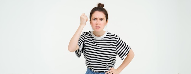 Bezpłatne zdjęcie zdjęcie wściekłej kobiety grożącej drżeniem pięści z dezaprobatą i besztającej kogoś stojącego nad białym
