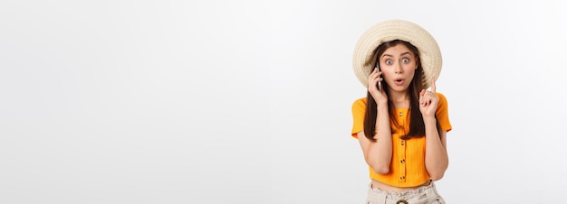 Zdjęcie zaskoczonej dziewczyny z podróży, która patrzy w szoku, trzymając telefon w dłoniach na białym tle na szarym tle