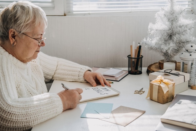 Zdrowe noworoczne postanowienia dla osób starszych, starszych, dojrzałych, staruszków w białym swetrze piszącym