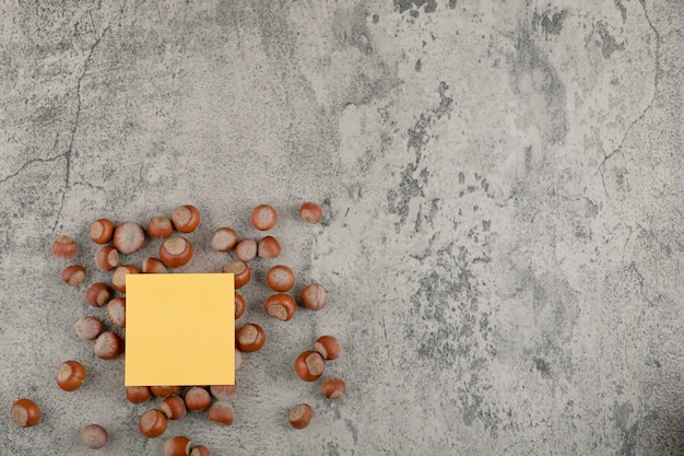 Zdrowe orzechy makadamia z żółtą kwadratową naklejką na kamiennym tle.