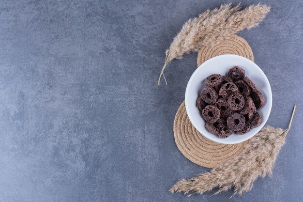 Zdrowe śniadanie z czekoladowymi krążkami kukurydzy w talerzu na kamiennej powierzchni