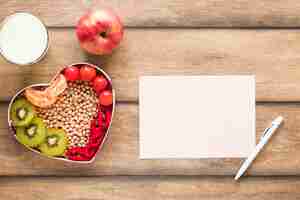 Bezpłatne zdjęcie zdrowe warzywa; owoce; mleko z pustego papieru i długopis na drewnianym stole