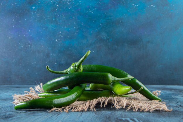 Zdrowe zielone papryczki chili umieszczone na niebieskim tle.