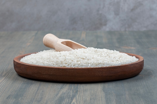 Zdrowy surowy ryż z drewnianą łyżką na drewnianym stole