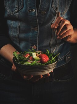 Zdrowy wegański lunch kobieta w niebieskim dżinsach trzyma ceramiczną miskę z grejpfrutem z awokado i sałatką z nerkowców w dłoniach komfort czystej wegetariańskiej diety