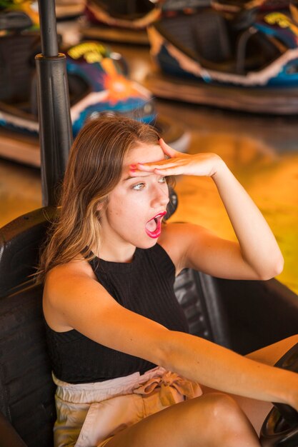 Zdziwiona młoda kobieta jedzie rekordowego samochód przy parkiem rozrywki