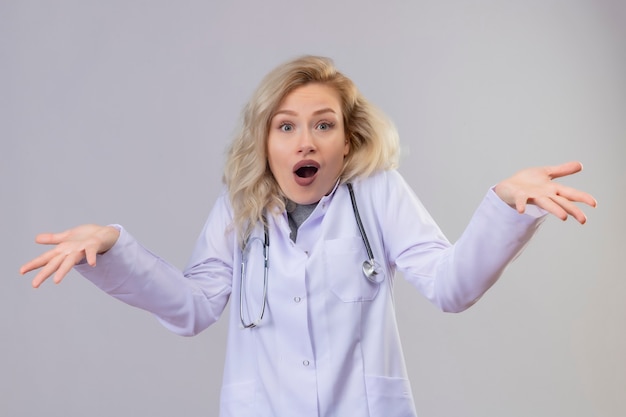 Zdziwiony Lekarz Młoda Dziewczyna Ubrana W Stetoskop W Sukni Medycznej Rozkłada Ręce Na Białym Tle