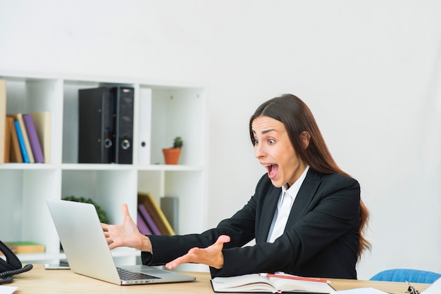 Zdziwiony młody bizneswoman patrzeje laptop