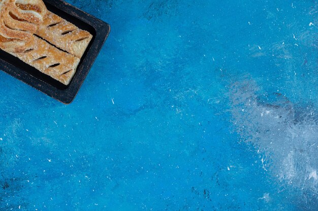 Zębate ciasteczka w drewnianej skrzynce na niebieskim tle. Wysokiej jakości zdjęcie