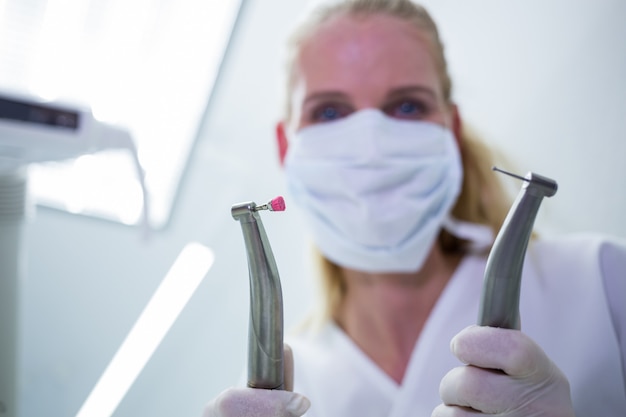 Żeński dentysta trzyma chirurgicznie instrumenty z maską chirurgiczną