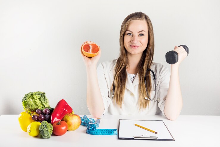 Bezpłatny plik Zdjęcie żeński dietician trzyma grapefruitowego i dumbbell w klinice