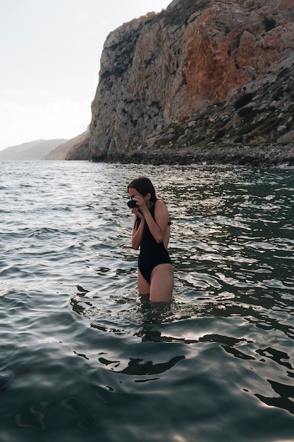 Żeński fotograf jest ubranym swimsuit bierze fotografię w morzu