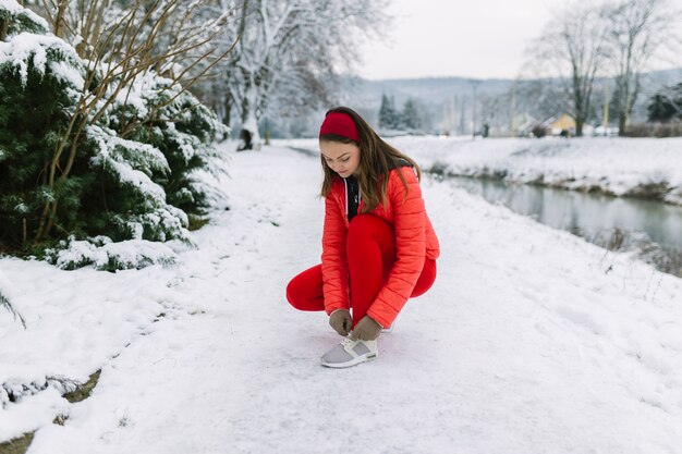 Żeński jogger wiąże shoelace blisko jeziora w zimie