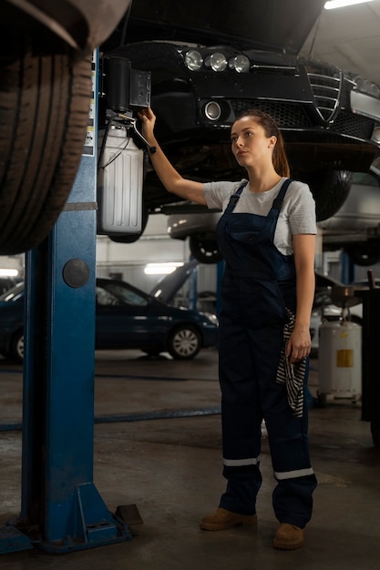 Żeński mechanik pracuje w sklepie na samochodzie