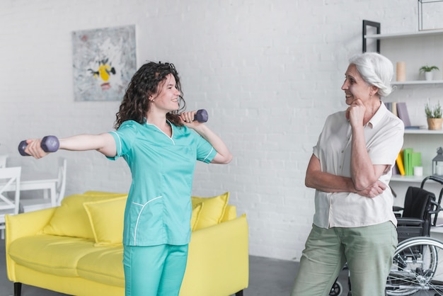 Bezpłatne zdjęcie Żeński terapeuta pomaga starszej kobiety z dumbbells