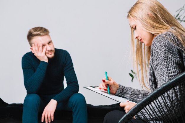 Żeńskiej blondynki młody psycholog konsultuje męskiego klienta podczas dyskusi terapii