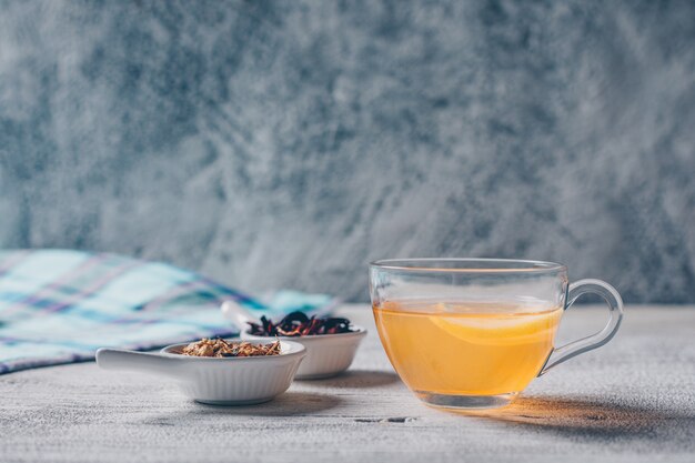 Zestaw herbacianych ziół i pomarańczy kolorowe wody na szarym tle. widok z boku.
