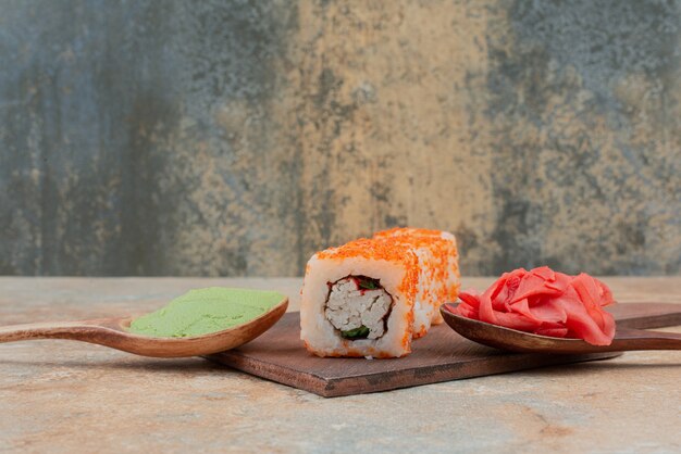 Zestaw pysznej rolki sushi z łyżeczką i sosem sojowym na marmurze