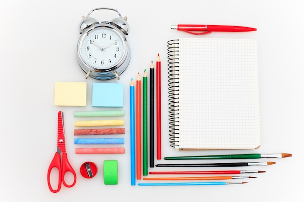 Zestaw szkolny z zeszytami, ołówkami, pędzlem, nożyczkami i jabłkiem na białym tle