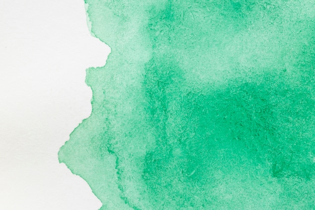 Zielona ręcznie malowana plama na białej powierzchni