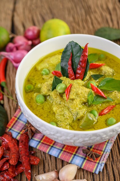 Zielone curry w misce z limonką, czerwoną cebulą, trawą cytrynową, czosnkiem i liśćmi limonki kaffir