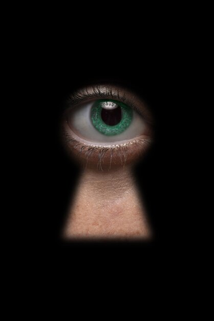 Zielone oko patrzące przez dziurkę od klucza