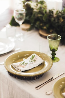 Zielone sztućce zdobione liśćmi roślin i białe serwetki na weselnym stole styl rustykalny