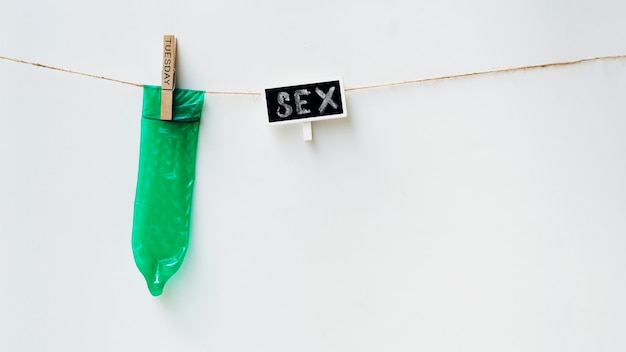 Zielony kondom na clothesline z białym tłem