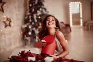Bezpłatne zdjęcie zimowe dekoracje świąteczne. ciepłe kolory. urocze kobiety brunetka w beżowej sukience
