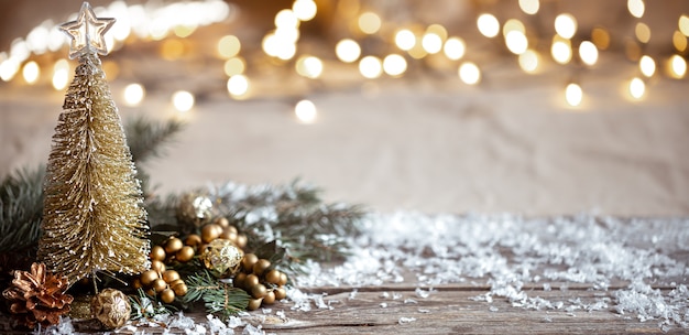 Zimowe przytulne tło z świątecznymi detalami dekoracyjnymi, śniegiem na drewnianym stole i bokeh. Koncepcja świątecznej atmosfery w domu.