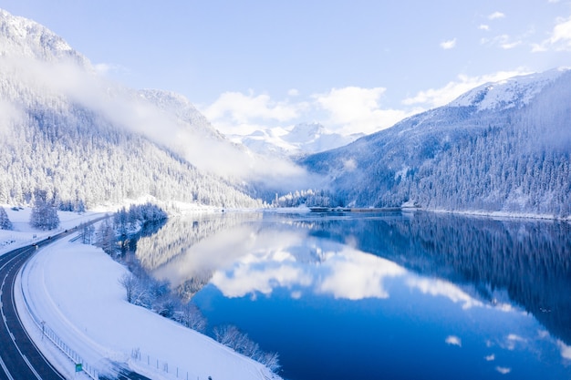 Zimowy krajobraz z mglistą mglistą górą i malowniczym kryształowym jeziorem górskim