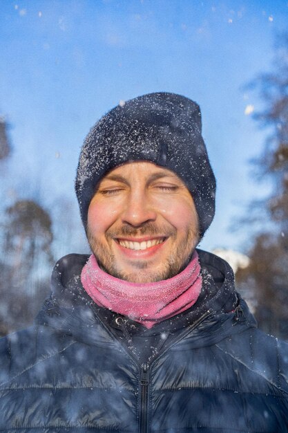 Zimowy portret młodego mężczyzny w zimowej czapce, cieszący się zimowymi chwilami