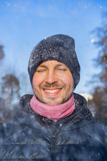 Zimowy portret młodego mężczyzny w zimowej czapce, cieszący się zimowymi chwilami