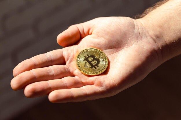Złoty bitcoin w dłoni mężczyzny