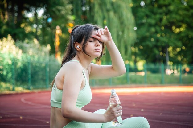 Zmęczona atrakcyjna kobieta po joggingu na stadionie